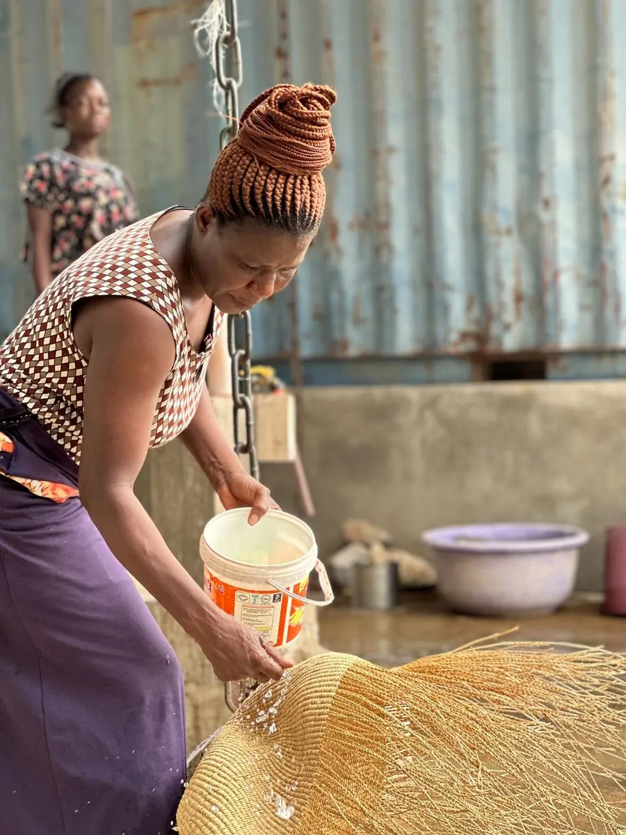 A basket maker dampening a basket beside a water bucket
