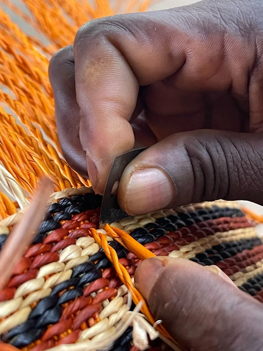Close view of hands trimming the edge of a colourful woven basket