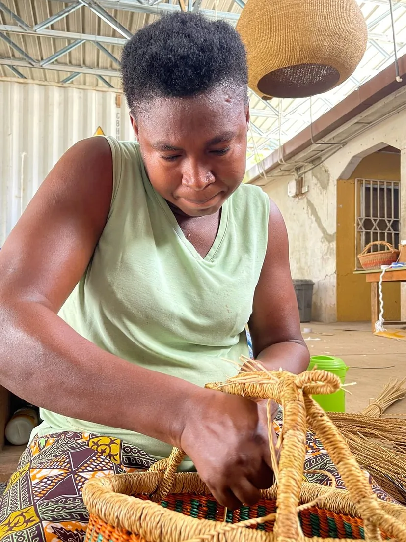 A basket maker shaping a straw handle by hand